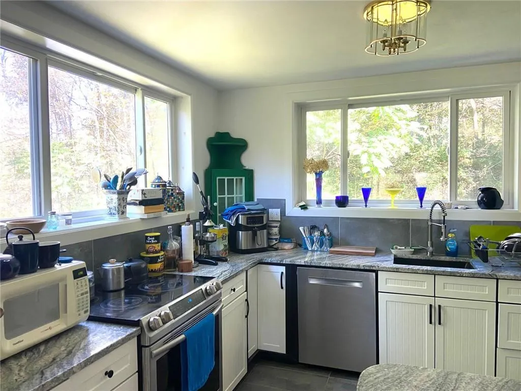 Kitchen featuring light stone counters, stainless steel appliances, and plenty of natural light Kitchen featuring light stone counters, stainless steel appliances, and plenty of natural light