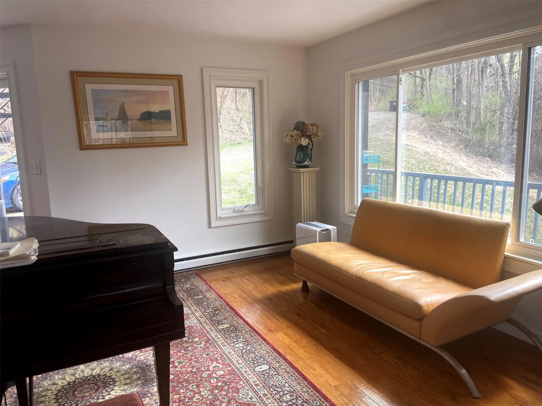 Sitting room featuring wood finished floors, a baseboard heating unit, and plenty of natural light Sitting room featuring wood finished floors, a baseboard heating unit, and plenty of natural light