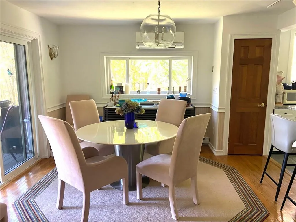 Dining space featuring light hardwood / wood-style flooring, a wall unit AC, and a chandelier Dining space featuring light hardwood / wood-style flooring, a wall unit AC, and a chandelier