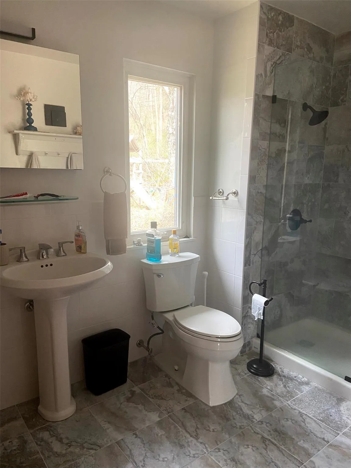 Bathroom featuring toilet, a shower stall, a sink, and tile walls Bathroom featuring toilet, a shower stall, a sink, and tile walls