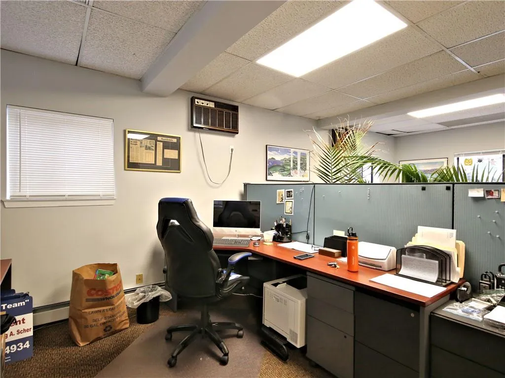 Office space with a wall mounted air conditioner, a baseboard heating unit, a paneled ceiling, and carpet floors Office space with a wall mounted air conditioner, a baseboard heating unit, a paneled ceiling, and carpet floors