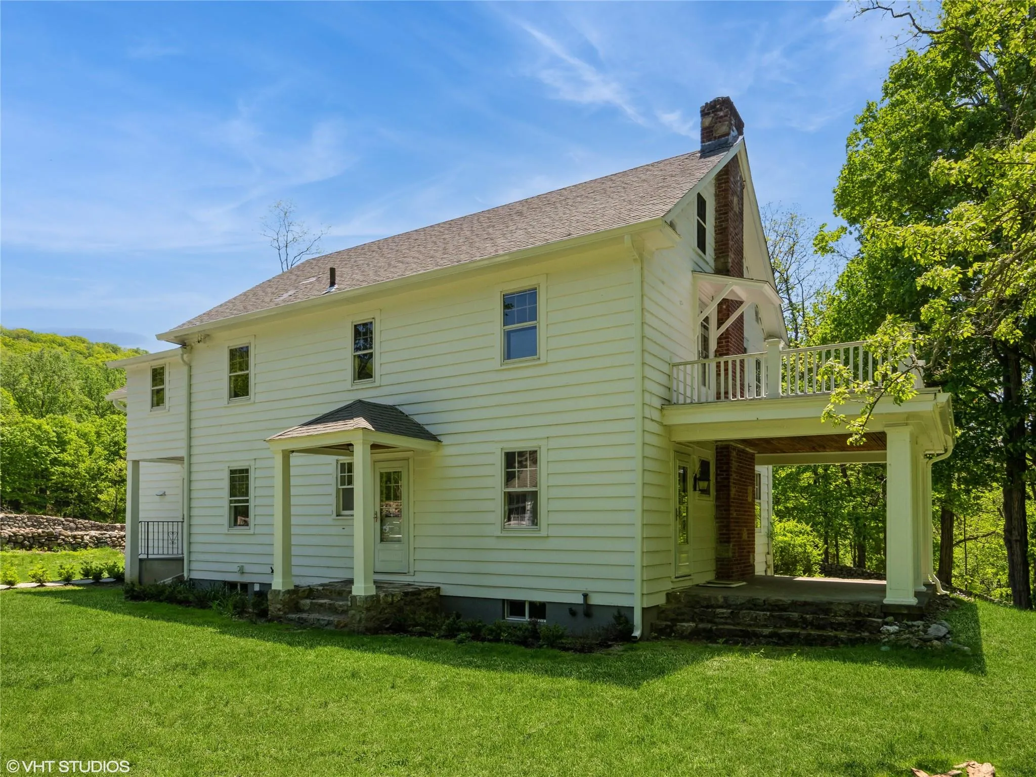 Rear view of house featuring a chimney, a balcony, and a yard Rear view of house featuring a chimney, a balcony, and a yard