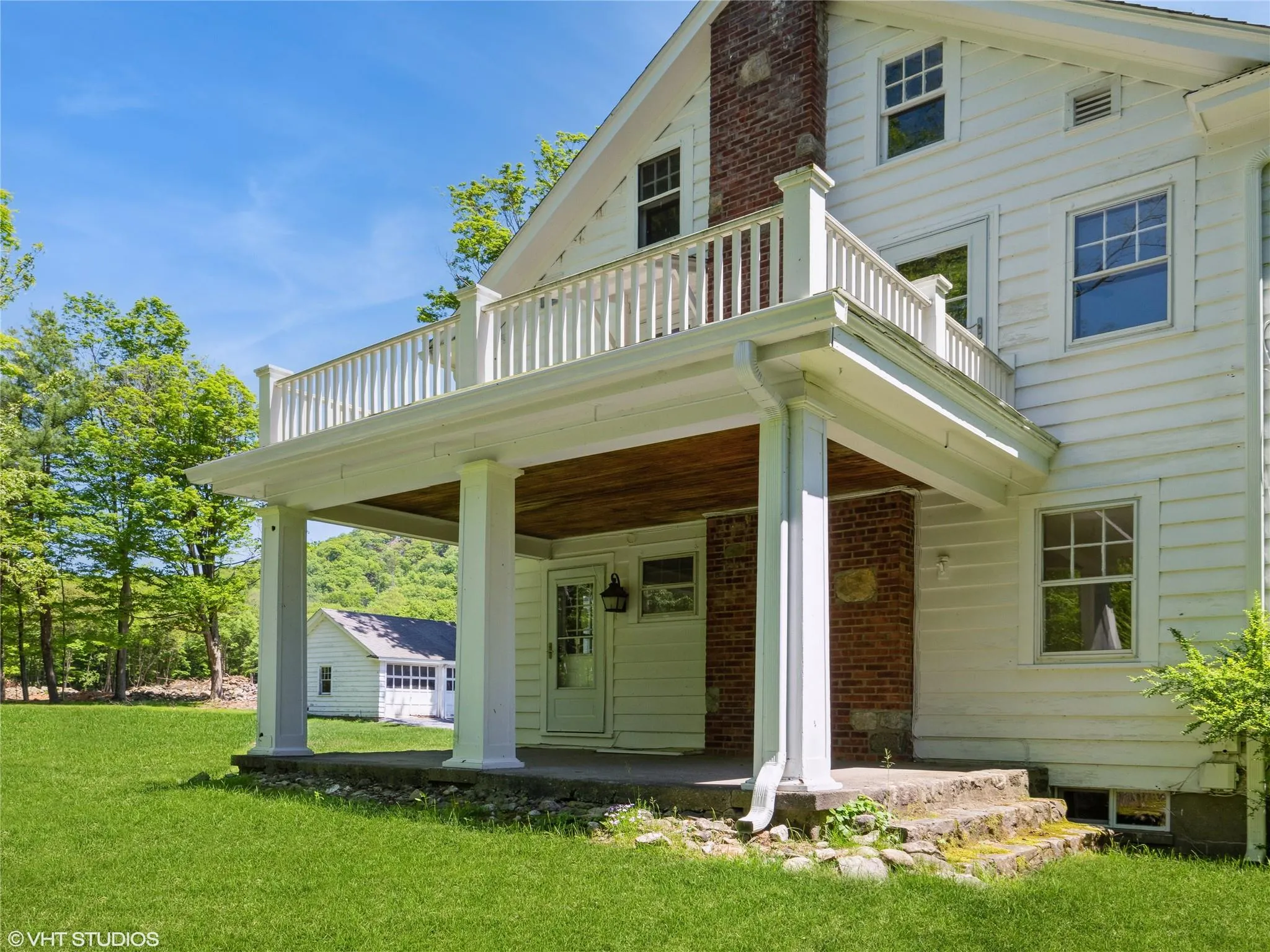Back of property featuring a balcony, a lawn, and a porch Back of property featuring a balcony, a lawn, and a porch