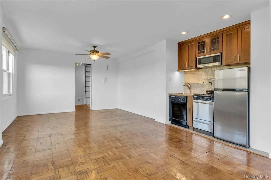 Kitchen with stainless steel appliances, light parquet floors, sink, ceiling fan, and backsplash Kitchen with stainless steel appliances, light parquet floors, sink, ceiling fan, and backsplash