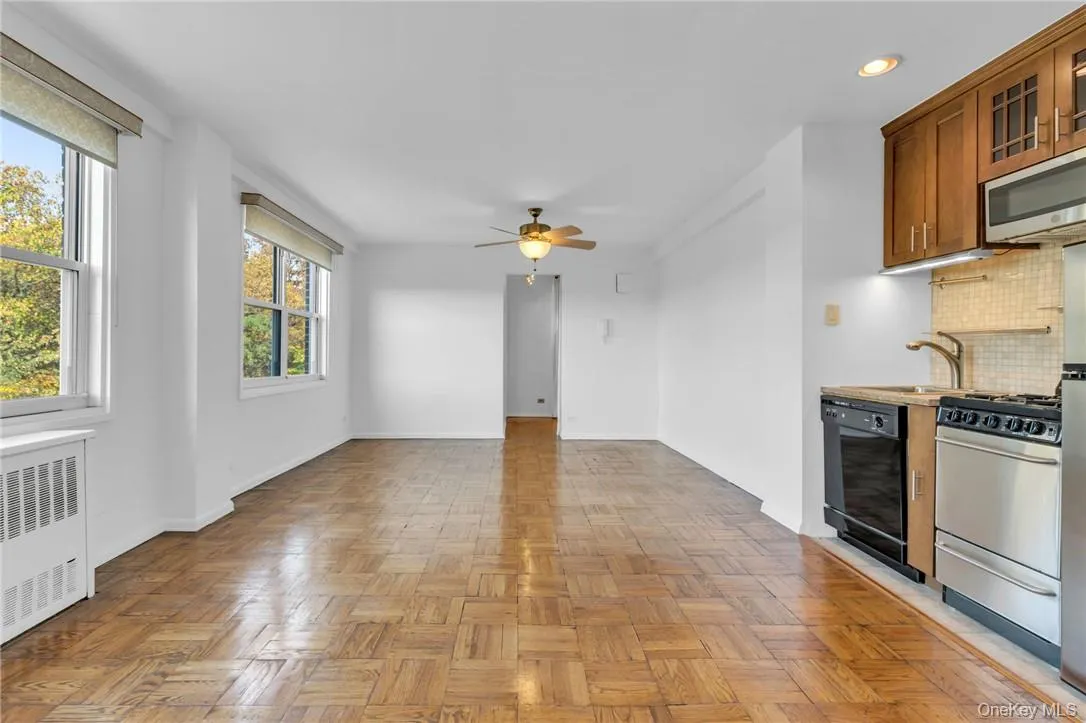 Kitchen featuring stainless steel appliances, sink, tasteful backsplash, light parquet flooring, and radiator heating unit Kitchen featuring stainless steel appliances, sink, tasteful backsplash, light parquet flooring, and radiator heating unit
