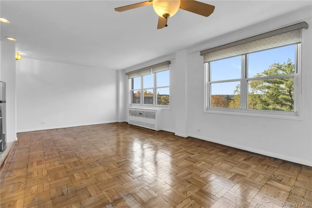 Empty room featuring radiator, ceiling fan, and dark parquet floors Empty room featuring radiator, ceiling fan, and dark parquet floors