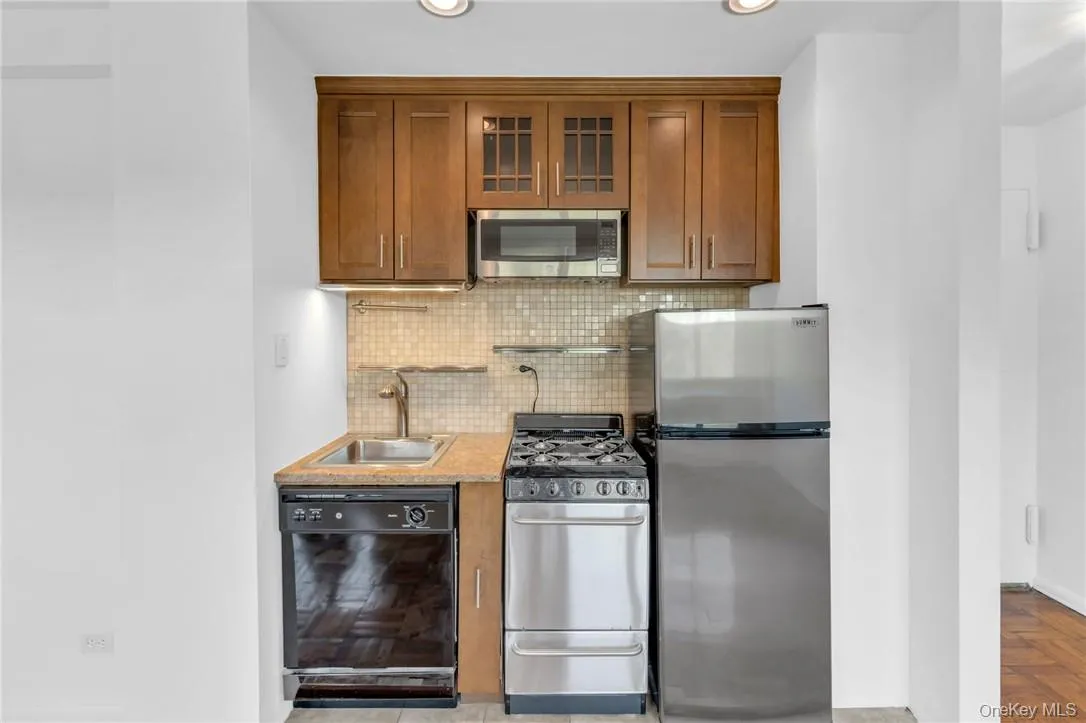 Kitchen with tasteful backsplash, light parquet flooring, sink, and stainless steel appliances Kitchen with tasteful backsplash, light parquet flooring, sink, and stainless steel appliances