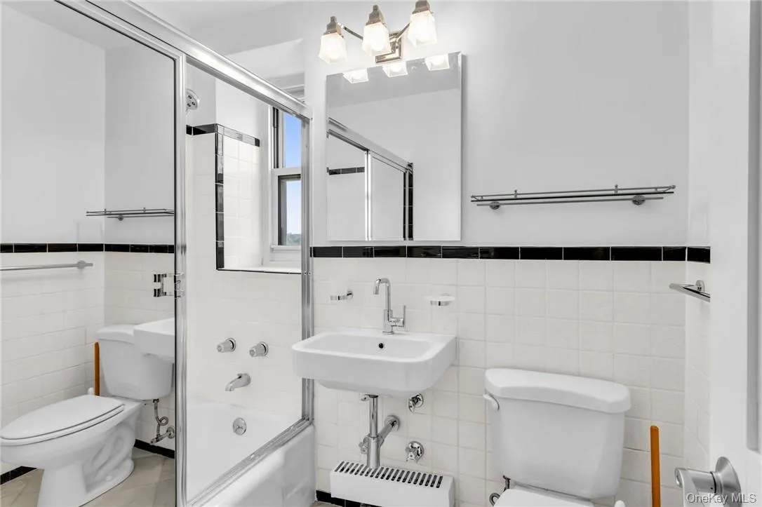 Full bathroom with enclosed tub / shower combo, toilet, and tile walls Full bathroom with enclosed tub / shower combo, toilet, and tile walls