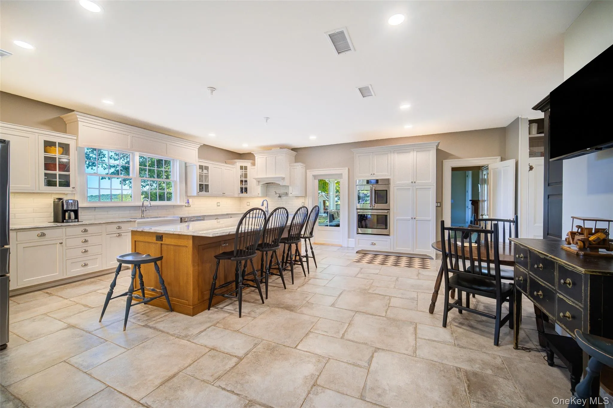 Kitchen with glass insert cabinets, white cabinets, light stone countertops, brown cabinetry, and recessed lighting Kitchen with glass insert cabinets, white cabinets, light stone countertops, brown cabinetry, and recessed lighting