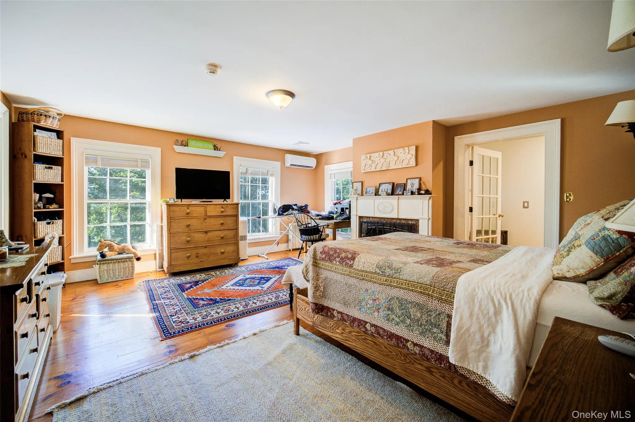 Bedroom with a fireplace, hardwood / wood-style flooring, and a wall mounted air conditioner Bedroom with a fireplace, hardwood / wood-style flooring, and a wall mounted air conditioner