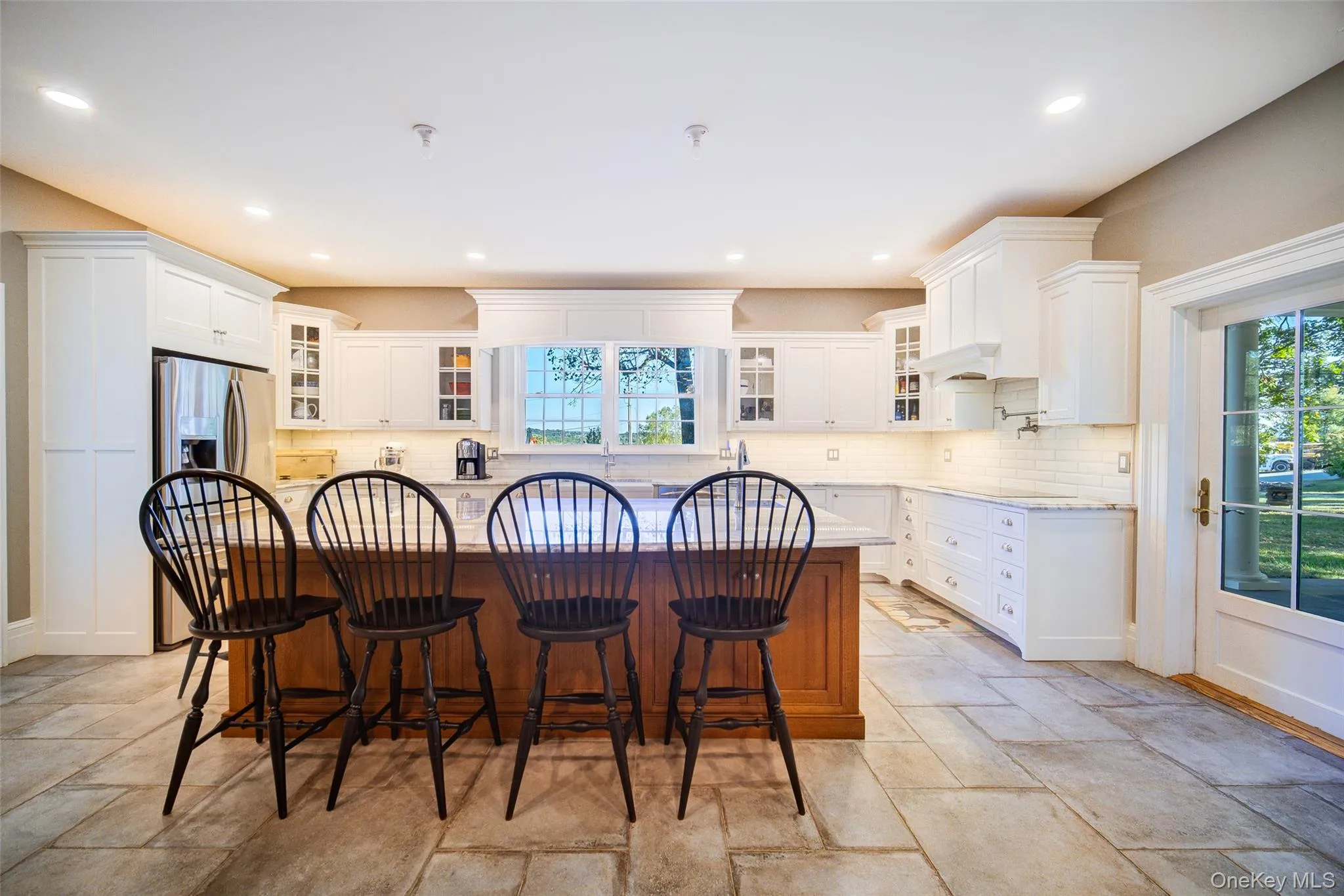Kitchen with glass insert cabinets, a breakfast bar, white cabinets, and recessed lighting Kitchen with glass insert cabinets, a breakfast bar, white cabinets, and recessed lighting
