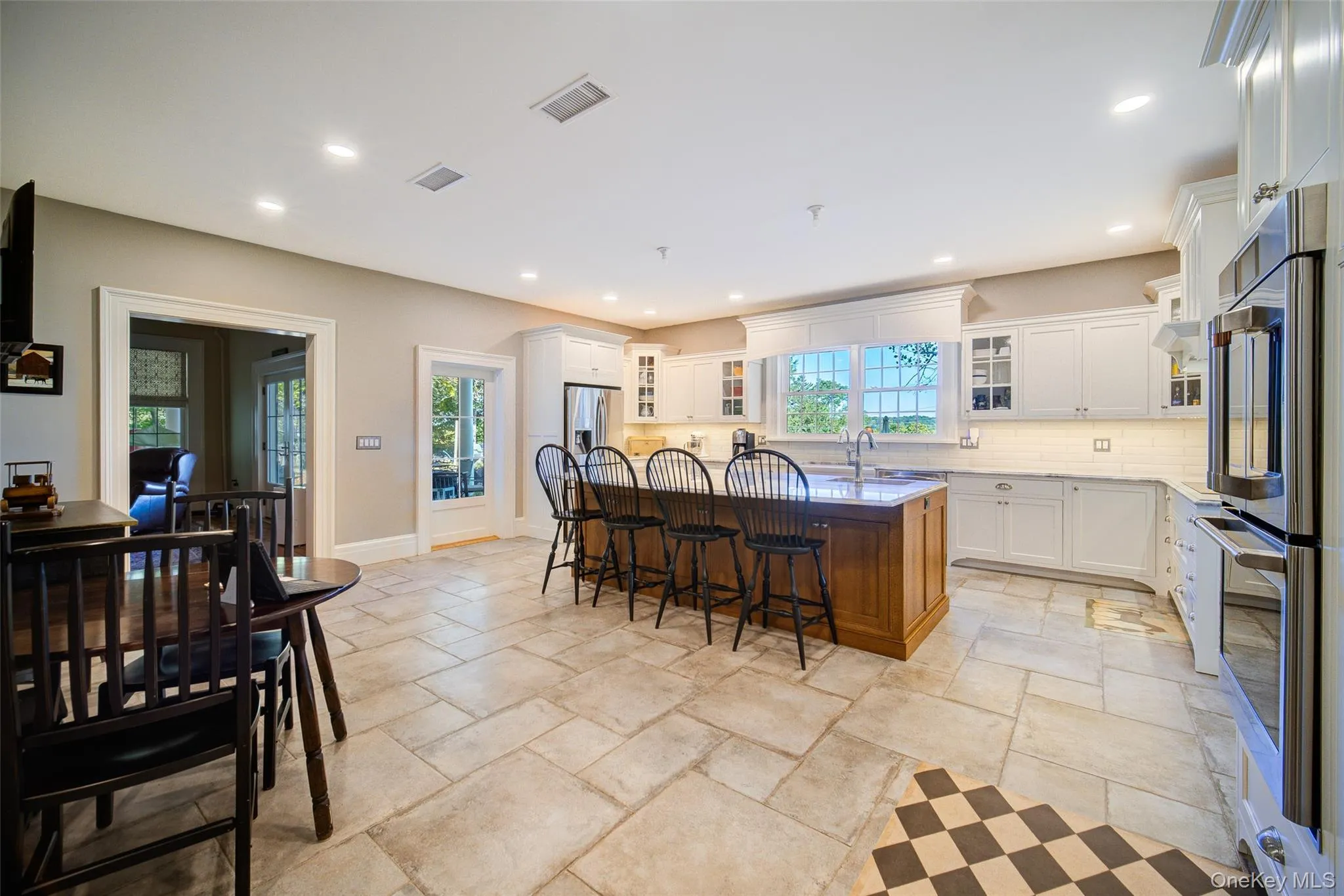 Kitchen featuring glass insert cabinets, stainless steel appliances, white cabinets, backsplash, and a kitchen breakfast bar Kitchen featuring glass insert cabinets, stainless steel appliances, white cabinets, backsplash, and a kitchen breakfast bar
