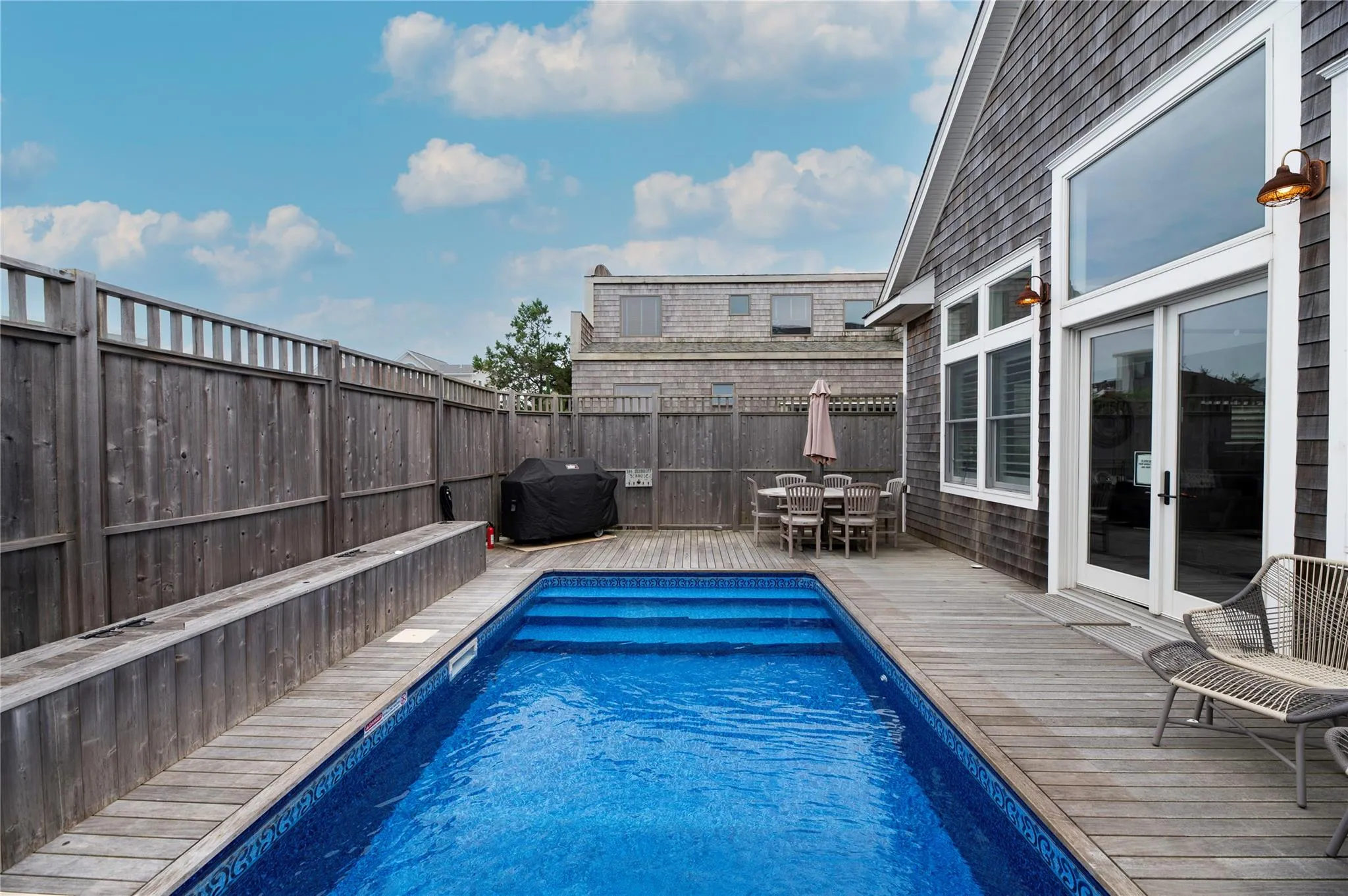 View of pool featuring a wooden deck and a grill View of pool featuring a wooden deck and a grill
