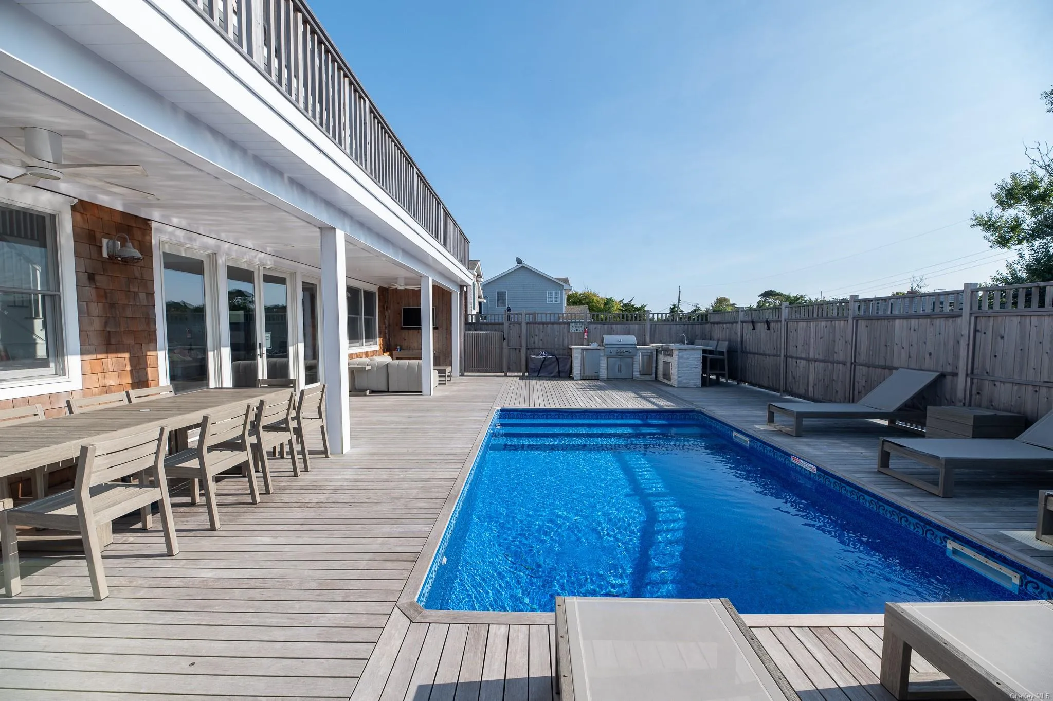 View of pool with a wooden deck, a grill, and ceiling fan View of pool with a wooden deck, a grill, and ceiling fan