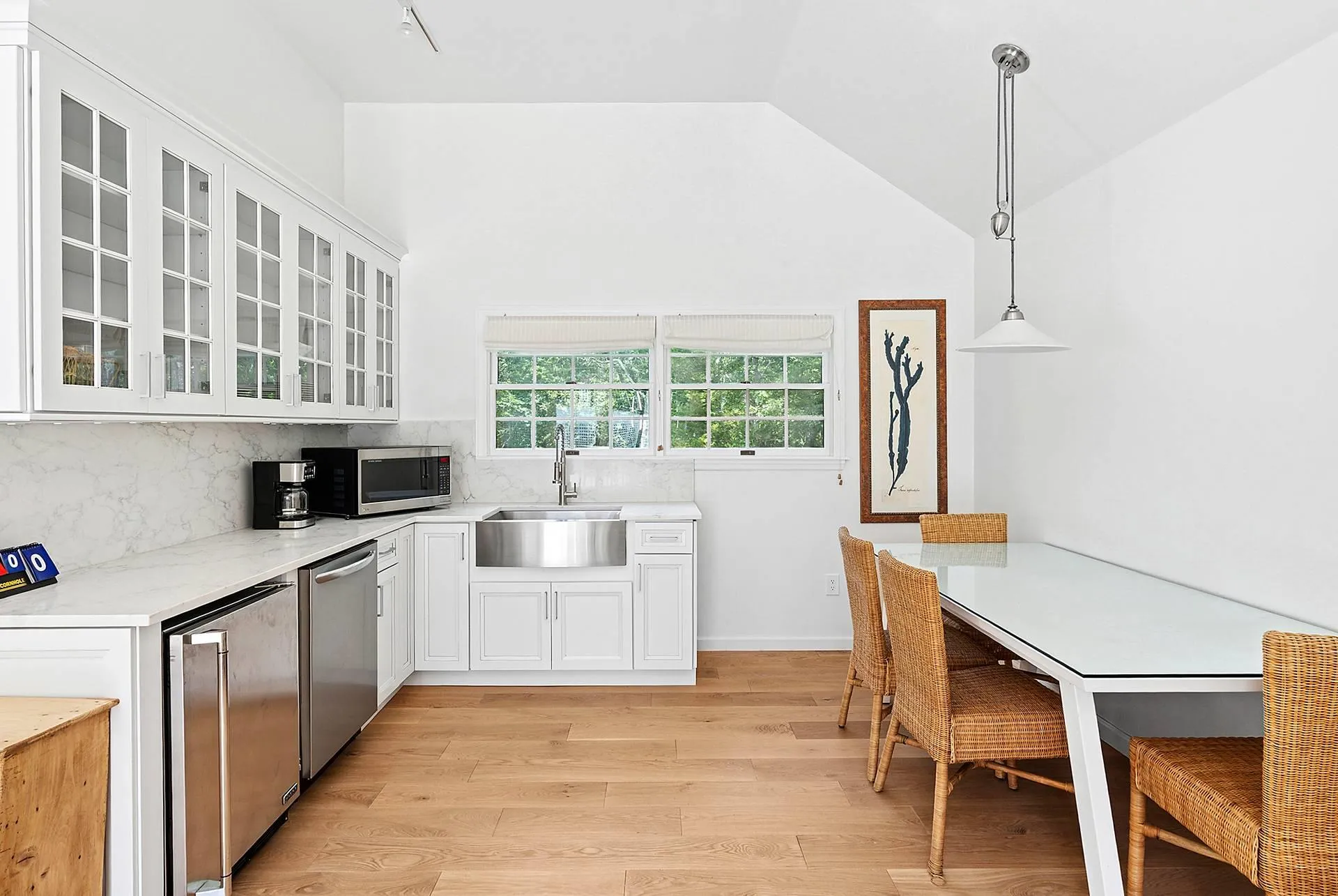 Kitchen featuring stainless steel appliances, white cabinetry, glass insert cabinets, light wood-style flooring, and backsplash Kitchen featuring stainless steel appliances, white cabinetry, glass insert cabinets, light wood-style flooring, and backsplash