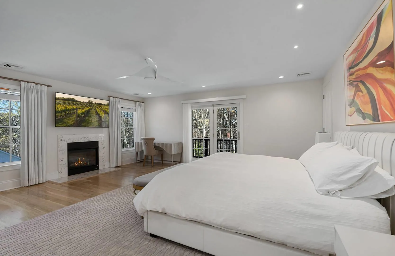 Bedroom featuring wood finished floors, access to exterior, multiple windows, recessed lighting, and a fireplace Bedroom featuring wood finished floors, access to exterior, multiple windows, recessed lighting, and a fireplace