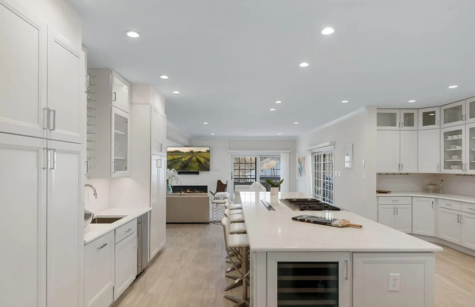Kitchen featuring beverage cooler, open floor plan, stainless steel gas cooktop, white cabinets, and light wood finished floors Kitchen featuring beverage cooler, open floor plan, stainless steel gas cooktop, white cabinets, and light wood finished floors