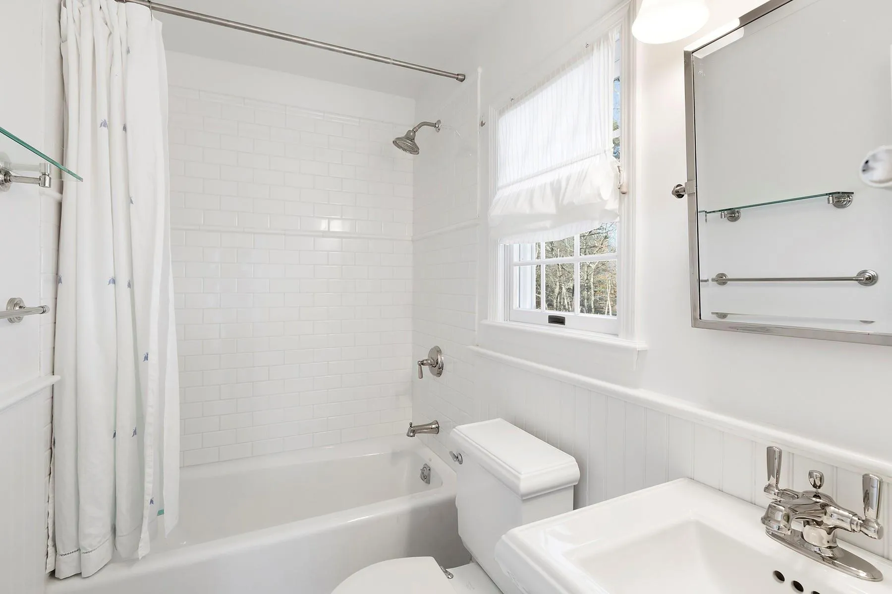 Full bathroom with shower / bathtub combination with curtain and a wainscoted wall Full bathroom with shower / bathtub combination with curtain and a wainscoted wall