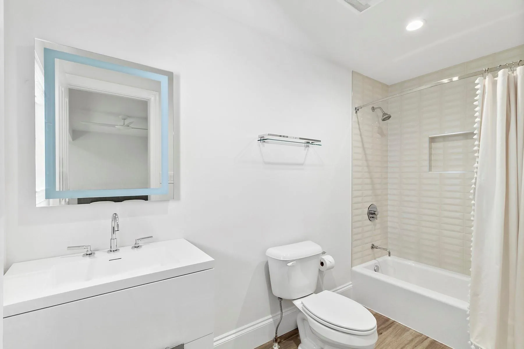 Full bathroom with shower / bathtub combination with curtain, vanity, and wood finished floors Full bathroom with shower / bathtub combination with curtain, vanity, and wood finished floors