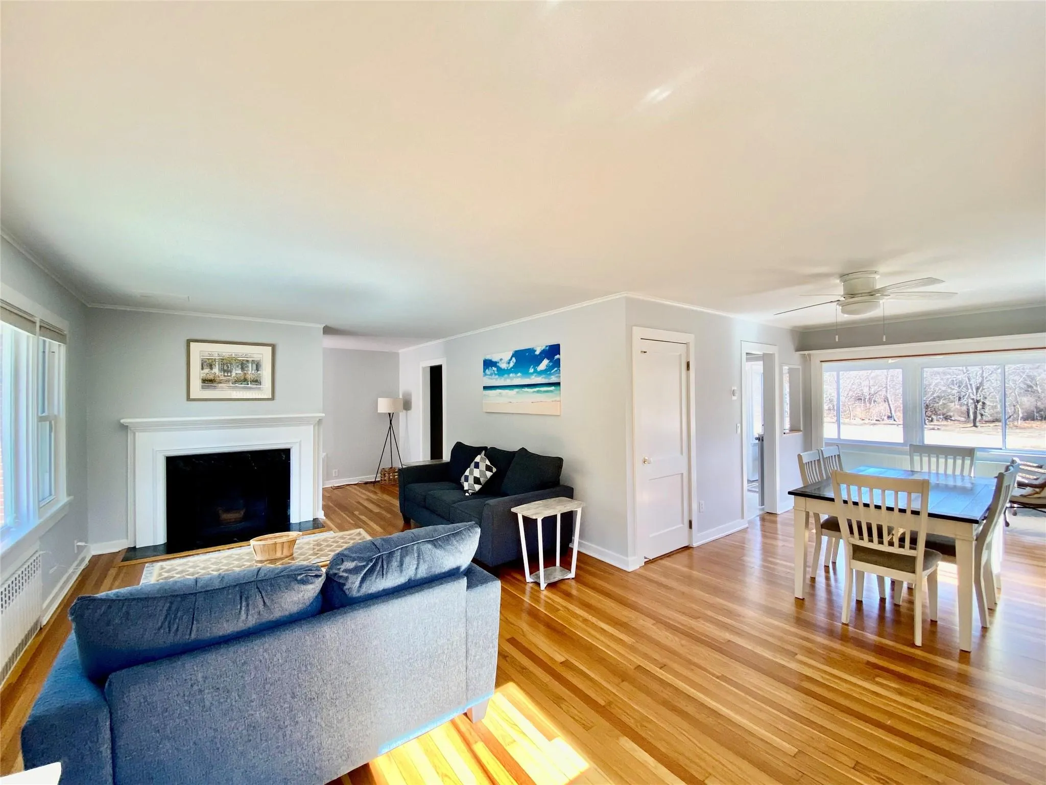 Living room with baseboards, ceiling fan, light wood-style flooring, ornamental molding, and a fireplace with flush hearth Living room with baseboards, ceiling fan, light wood-style flooring, ornamental molding, and a fireplace with flush hearth