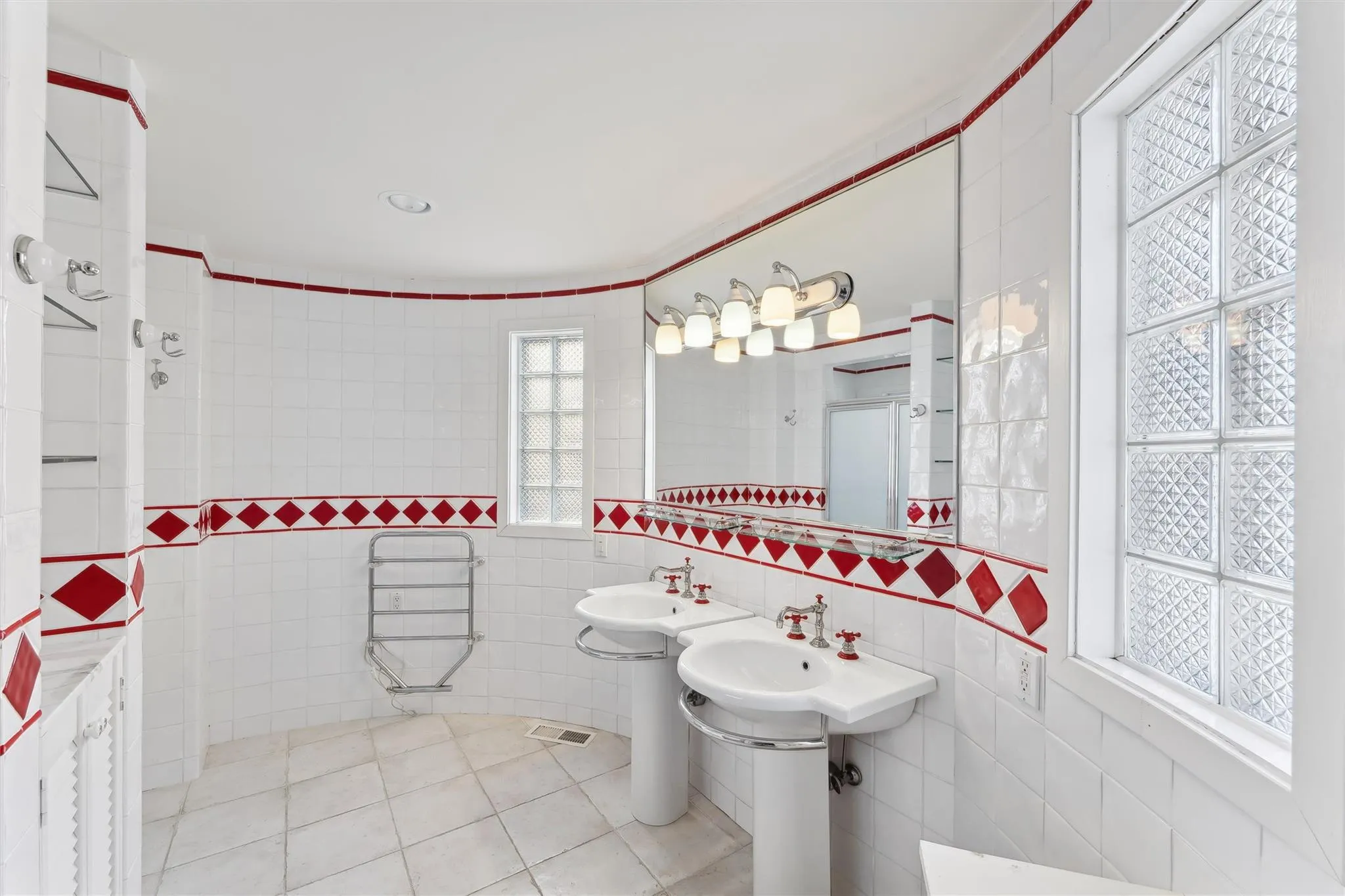 Bathroom with tile patterned floors, double sink, and tile walls Bathroom with tile patterned floors, double sink, and tile walls