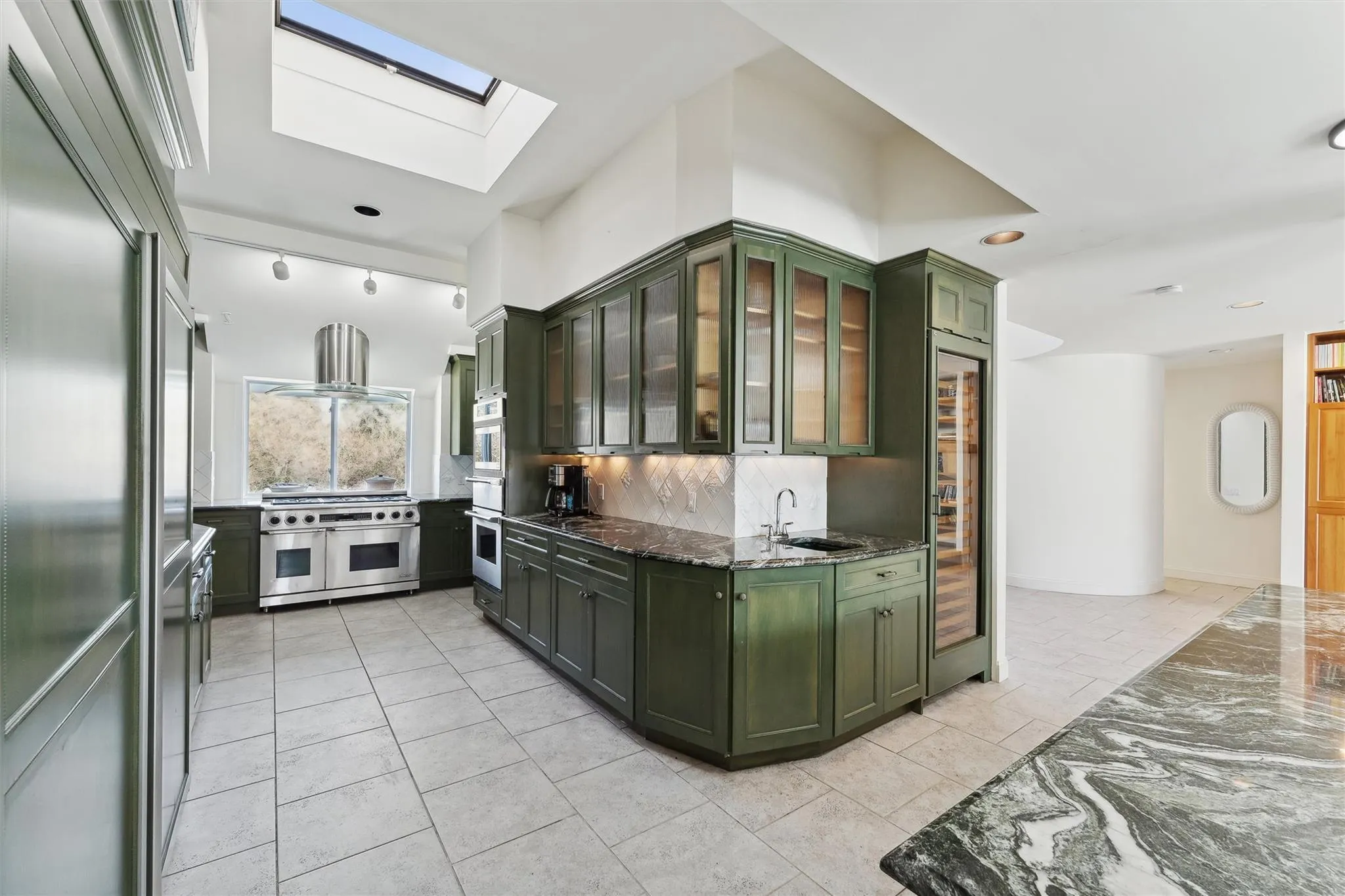 Kitchen featuring premium appliances, a skylight, extractor fan, and dark stone counters Kitchen featuring premium appliances, a skylight, extractor fan, and dark stone counters