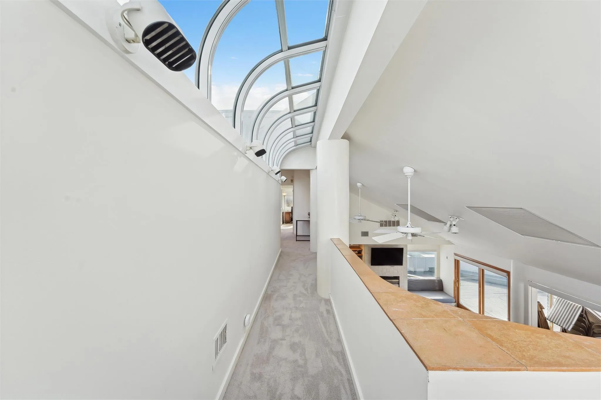 Corridor with light carpet, high vaulted ceiling, and a healthy amount of sunlight Corridor with light carpet, high vaulted ceiling, and a healthy amount of sunlight