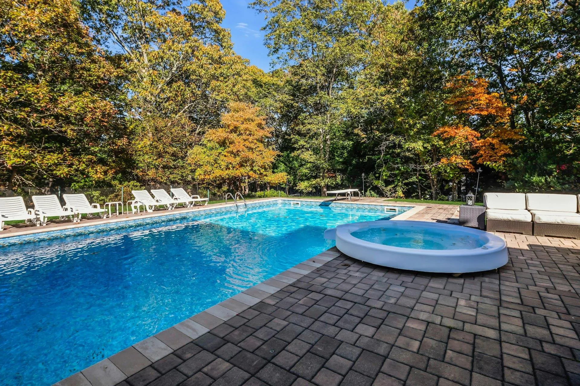 View of pool featuring a patio area, a diving board, and a pool with connected hot tub View of pool featuring a patio area, a diving board, and a pool with connected hot tub
