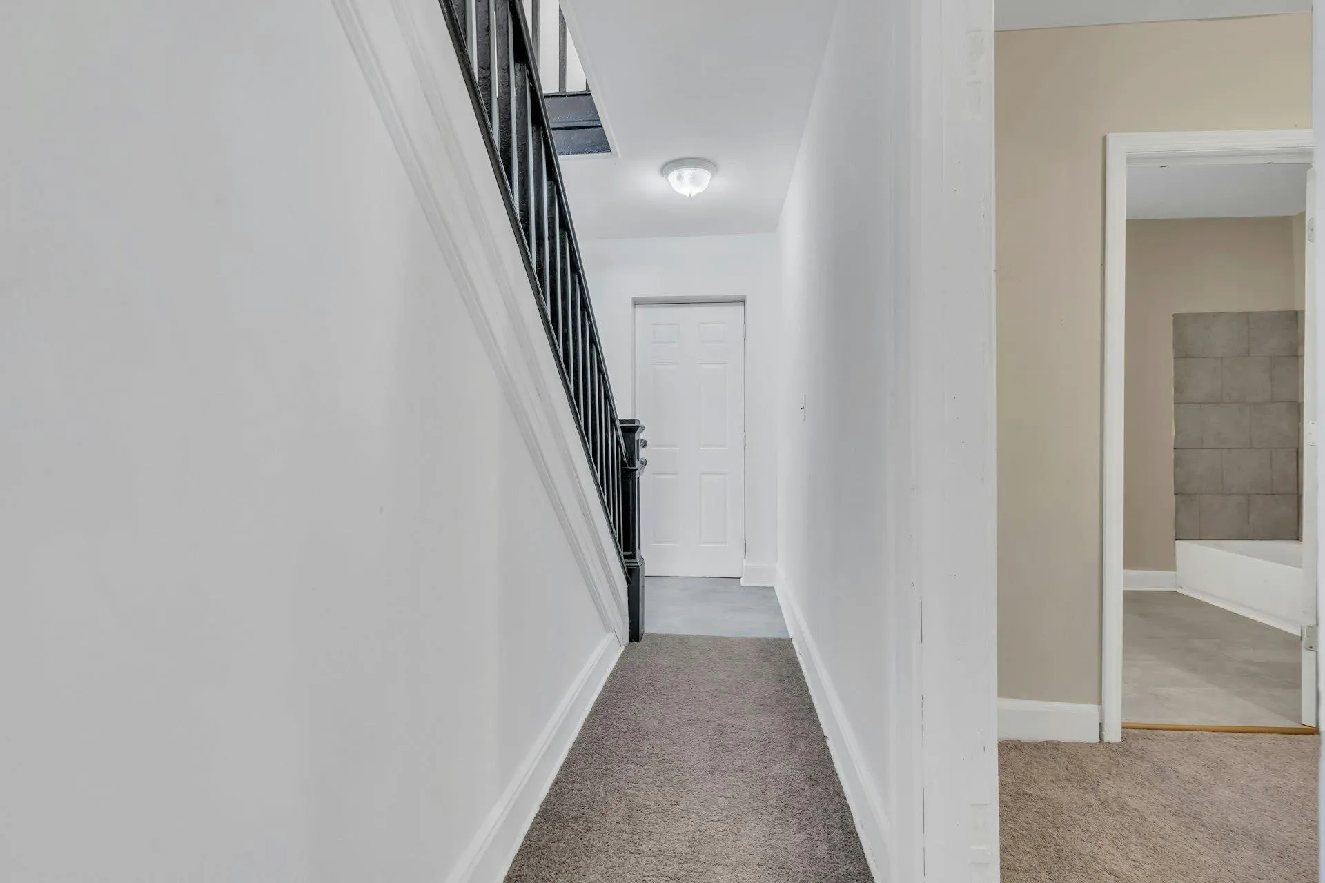 Hallway featuring stairway and light colored carpet Hallway featuring stairway and light colored carpet