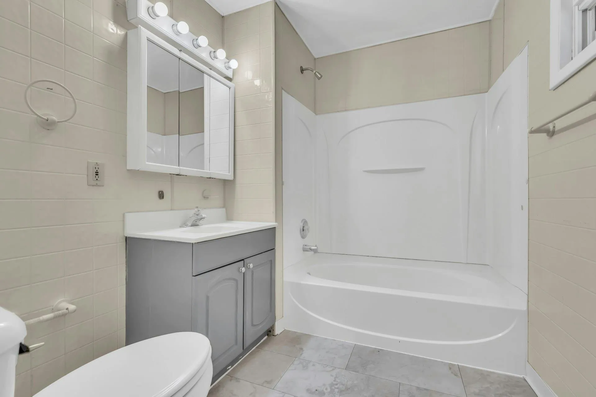 Bathroom featuring tile walls, vanity, and shower / washtub combination Bathroom featuring tile walls, vanity, and shower / washtub combination