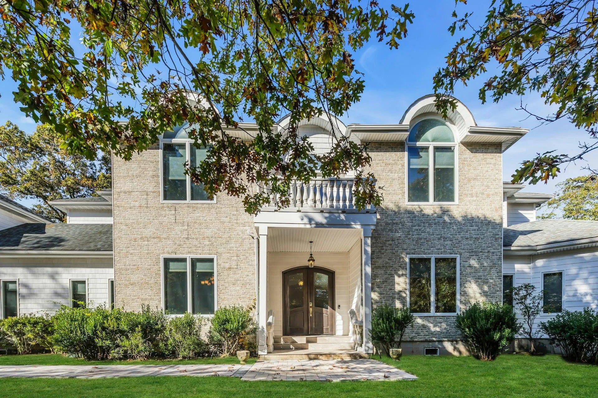 Traditional home featuring a front yard, brick siding, and a balcony Traditional home featuring a front yard, brick siding, and a balcony