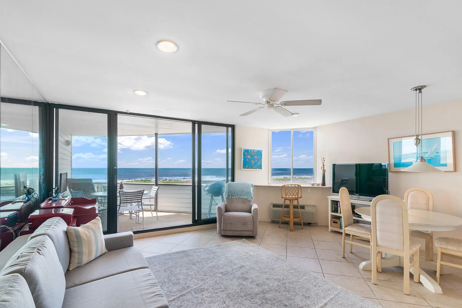 Tiled living area with a ceiling fan and a wall of windows Tiled living area with a ceiling fan and a wall of windows