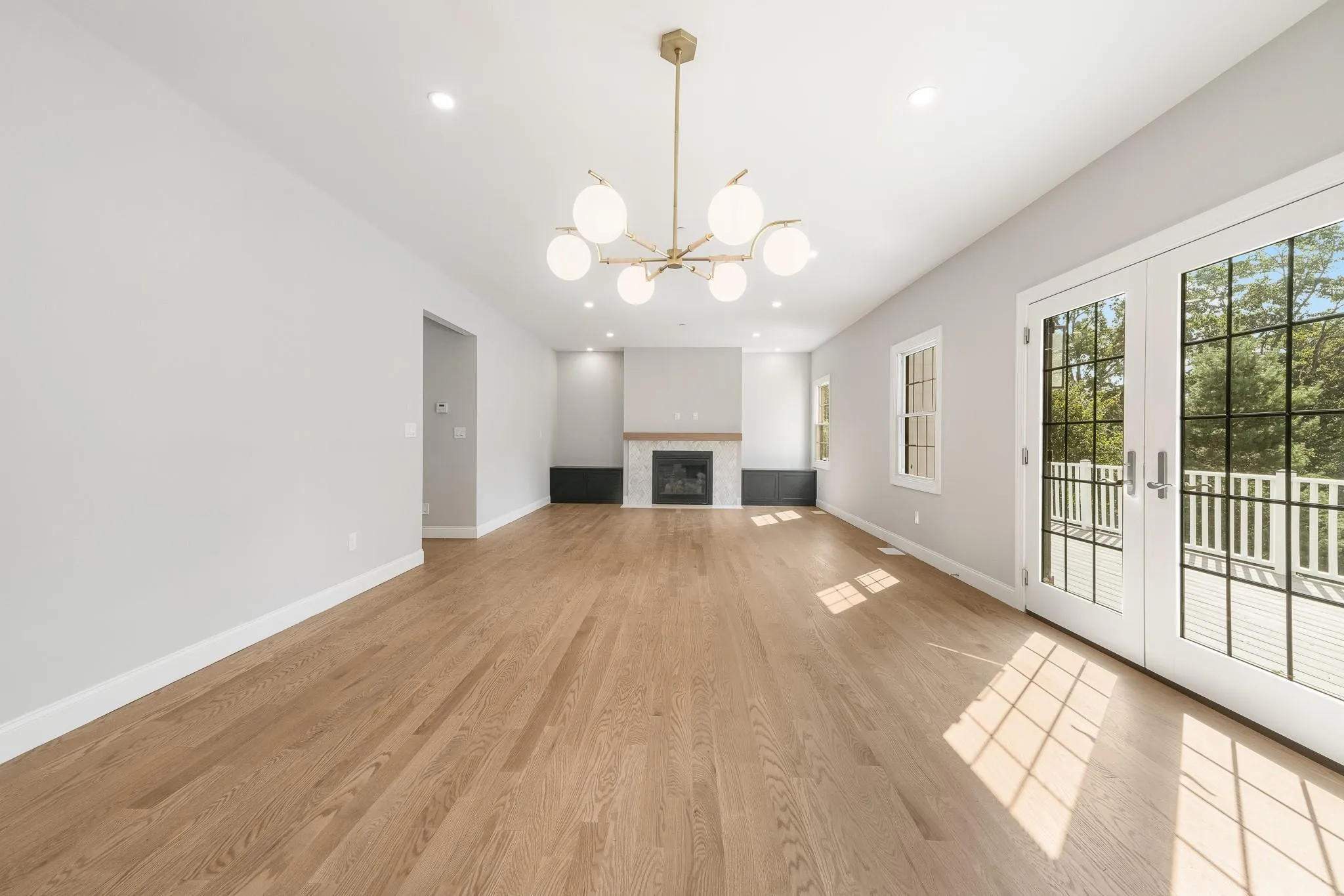 Unfurnished living room featuring a tiled fireplace, a notable chandelier, light hardwood / wood-style floors, and french doors Unfurnished living room featuring a tiled fireplace, a notable chandelier, light hardwood / wood-style floors, and french doors