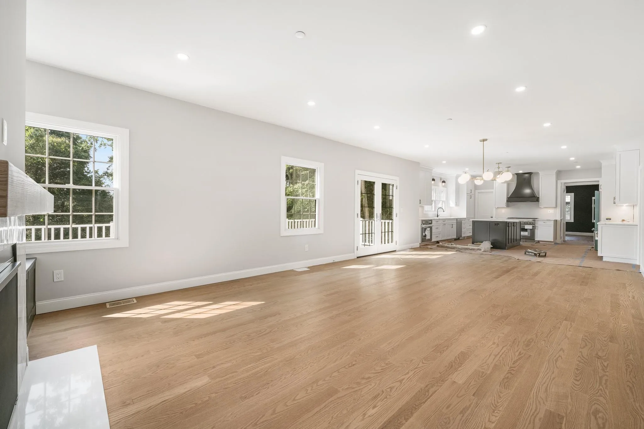 Unfurnished living room featuring sink, a notable chandelier, and light wood-type flooring Unfurnished living room featuring sink, a notable chandelier, and light wood-type flooring