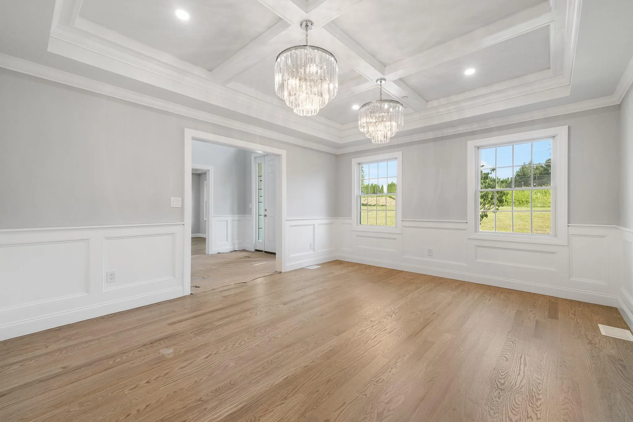 Unfurnished room featuring an inviting chandelier, coffered ceiling, ornamental molding, light hardwood / wood-style floors, and beamed ceiling Unfurnished room featuring an inviting chandelier, coffered ceiling, ornamental molding, light hardwood / wood-style floors, and beamed ceiling