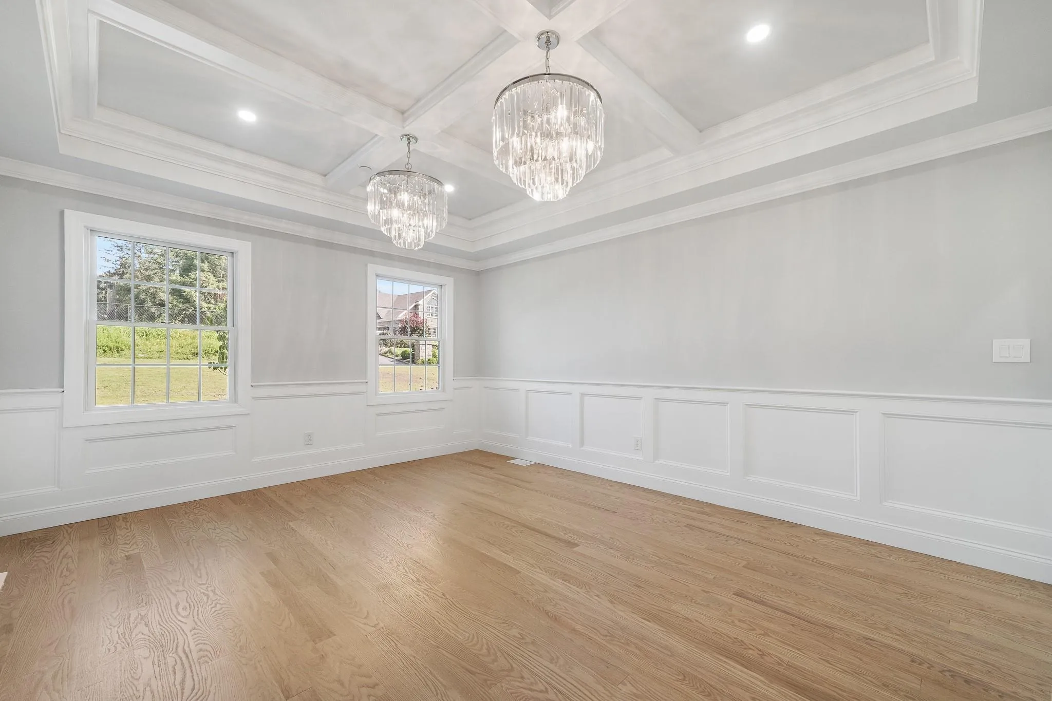 Empty room featuring beamed ceiling, coffered ceiling, an inviting chandelier, and light hardwood / wood-style flooring Empty room featuring beamed ceiling, coffered ceiling, an inviting chandelier, and light hardwood / wood-style flooring