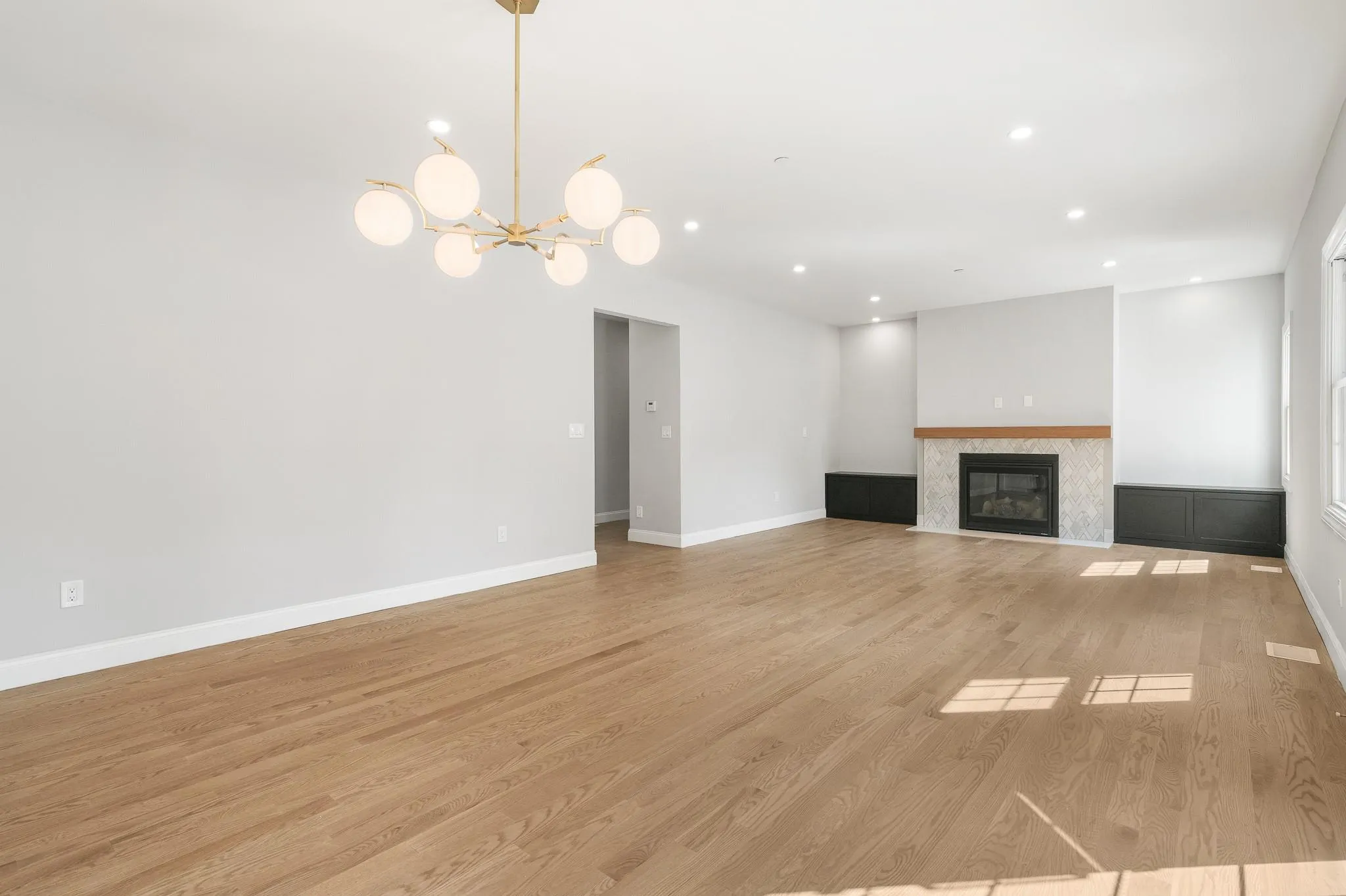 Unfurnished living room featuring an inviting chandelier and light hardwood / wood-style flooring Unfurnished living room featuring an inviting chandelier and light hardwood / wood-style flooring