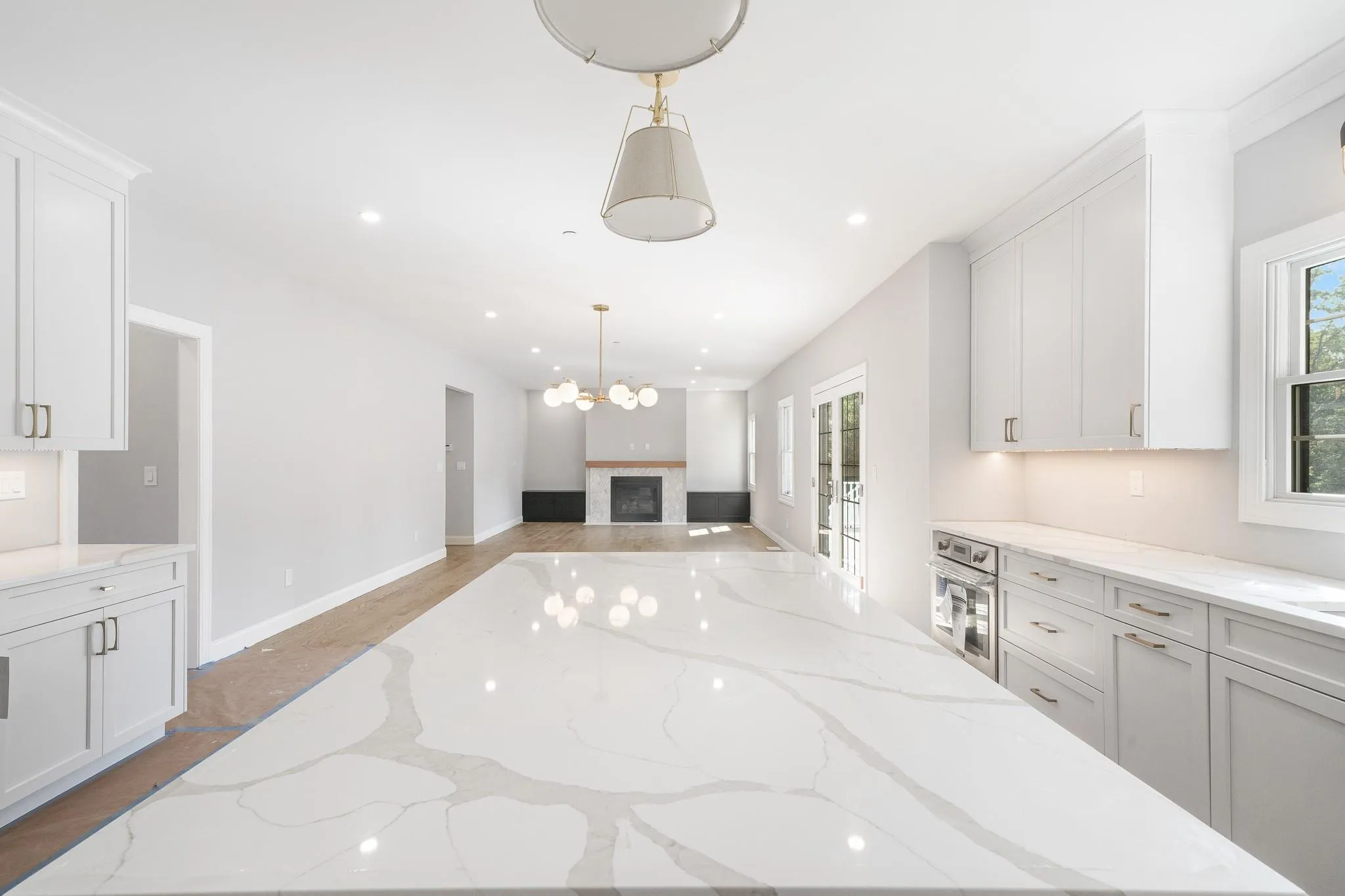 Kitchen featuring light stone counters, hanging light fixtures, white cabinetry, and oven Kitchen featuring light stone counters, hanging light fixtures, white cabinetry, and oven