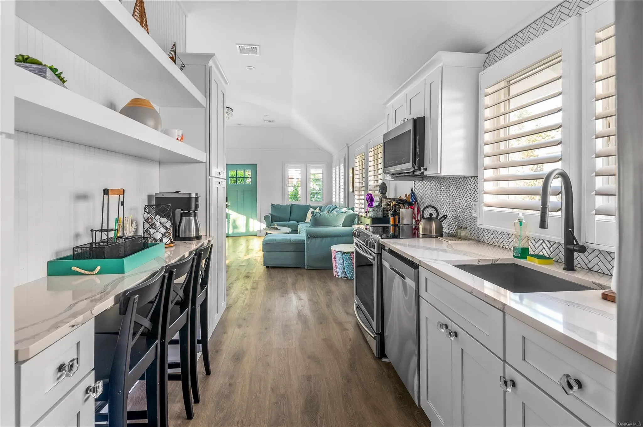 Kitchen with light stone counters, appliances with stainless steel finishes, vaulted ceiling, and sink Kitchen with light stone counters, appliances with stainless steel finishes, vaulted ceiling, and sink