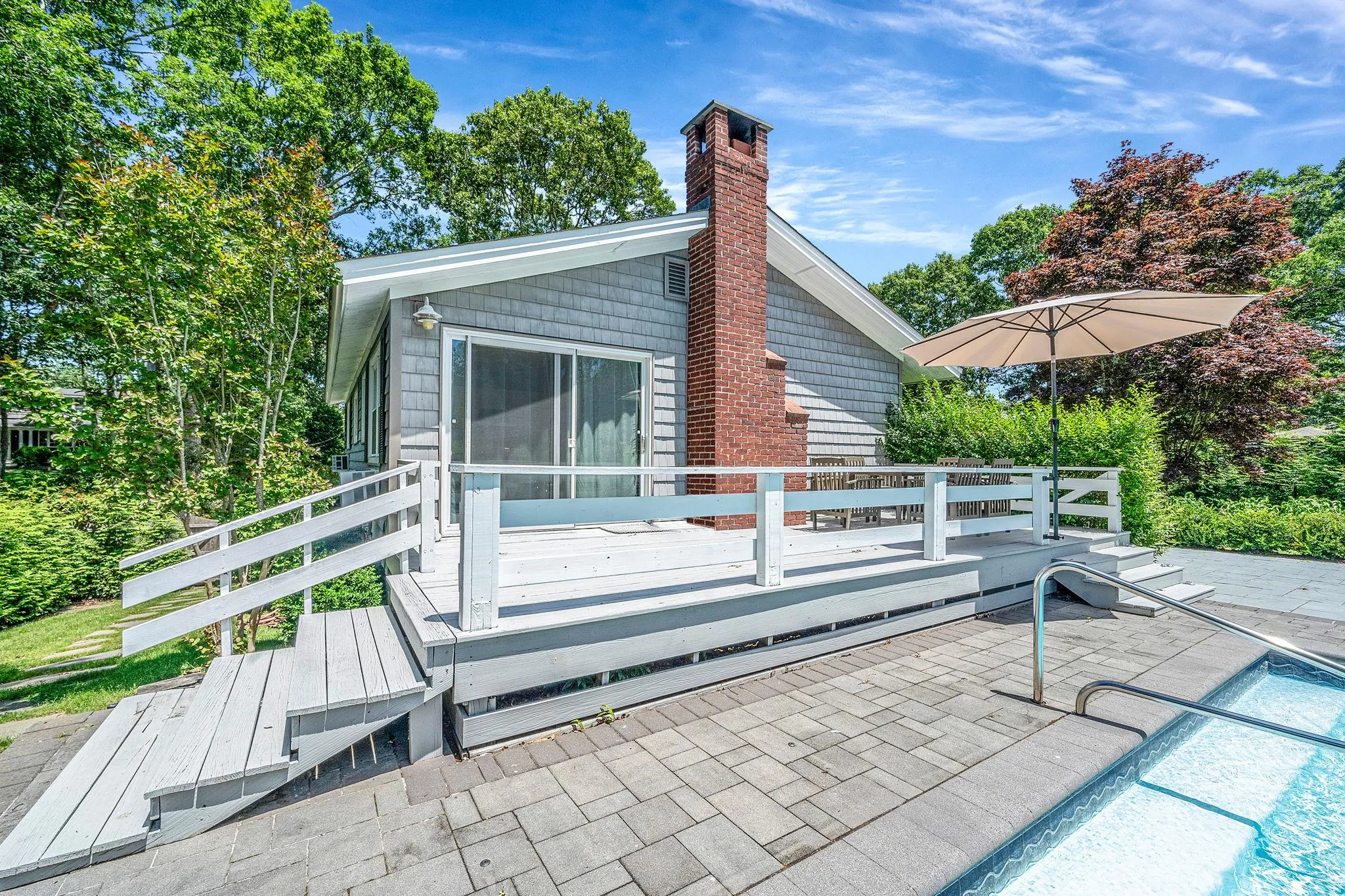 Back of house with a deck, a chimney, and a patio area Back of house with a deck, a chimney, and a patio area