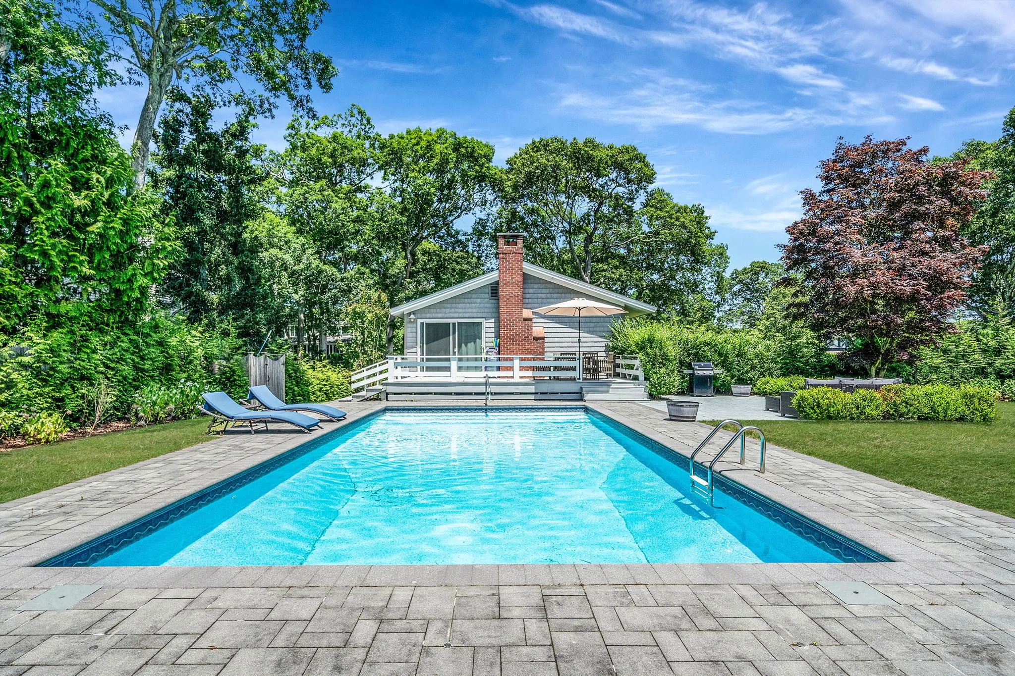 Swimming pool with a patio, a yard, and view of scattered trees Swimming pool with a patio, a yard, and view of scattered trees