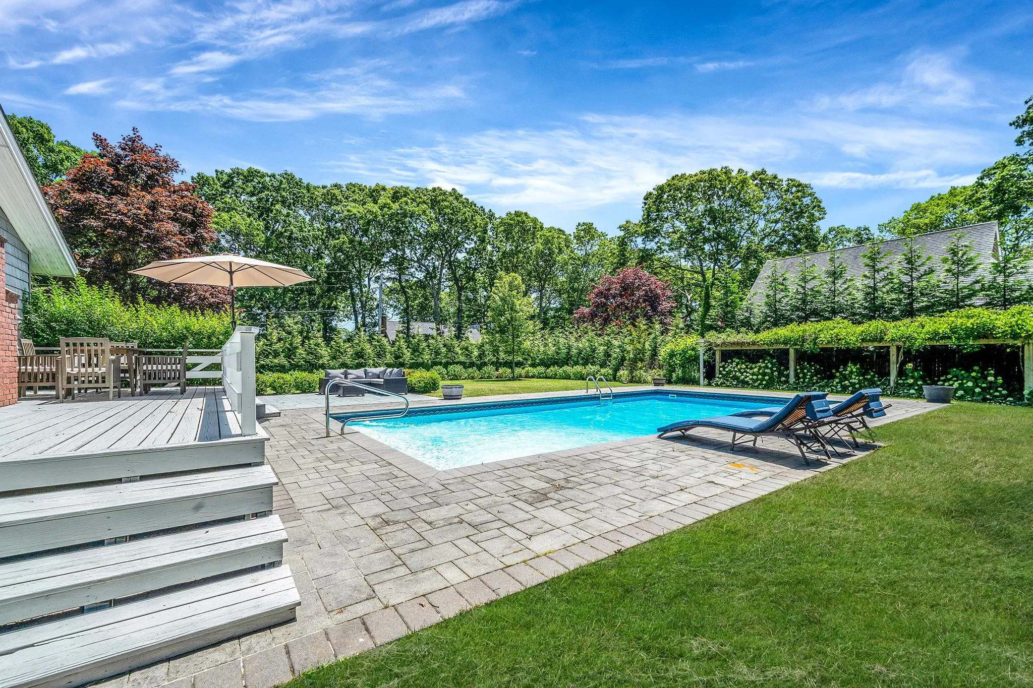 Swimming pool featuring a yard, a deck, and a patio Swimming pool featuring a yard, a deck, and a patio