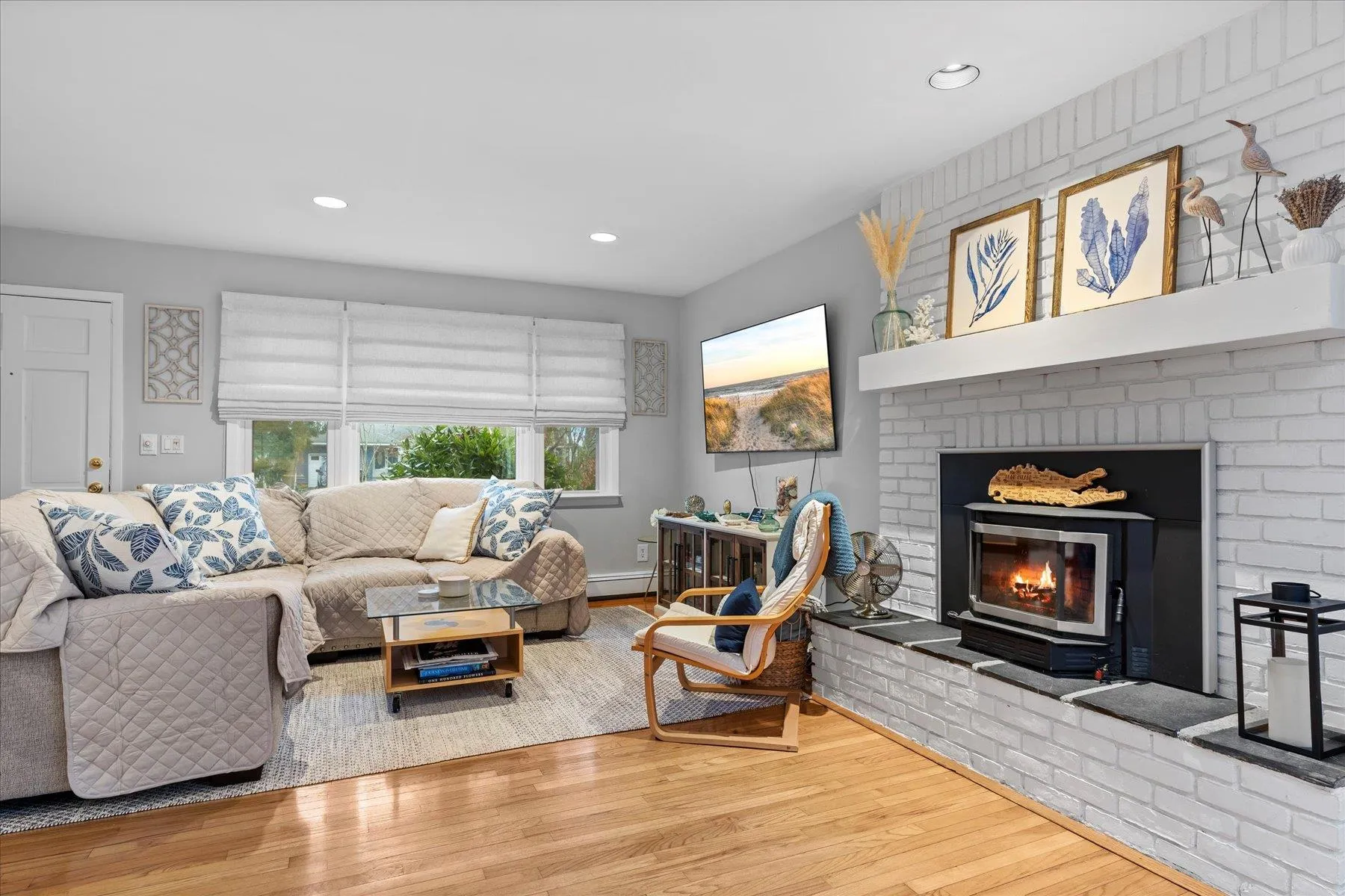 Living area featuring recessed lighting, wood finished floors, a brick fireplace, and baseboard heating Living area featuring recessed lighting, wood finished floors, a brick fireplace, and baseboard heating