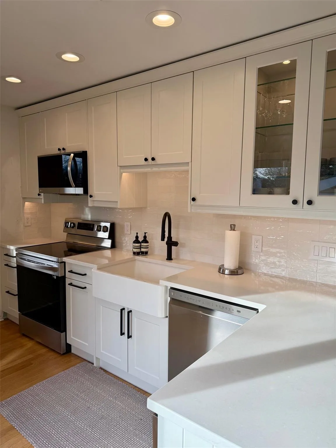 Kitchen with white cabinetry, sink, stainless steel appliances, and light hardwood / wood-style floors Kitchen with white cabinetry, sink, stainless steel appliances, and light hardwood / wood-style floors