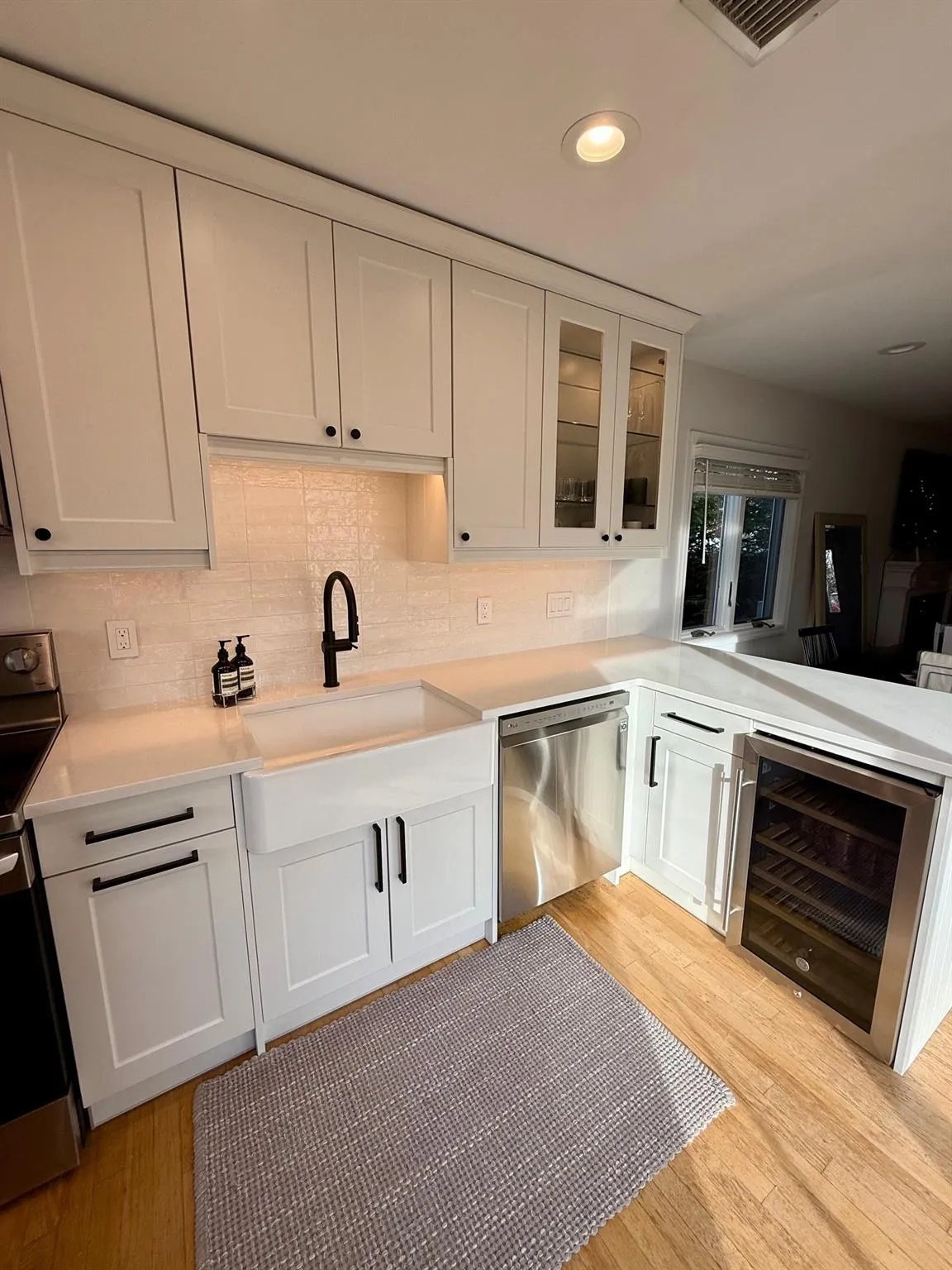 Kitchen with sink, wine cooler, light hardwood / wood-style floors, white cabinetry, and stainless steel appliances Kitchen with sink, wine cooler, light hardwood / wood-style floors, white cabinetry, and stainless steel appliances