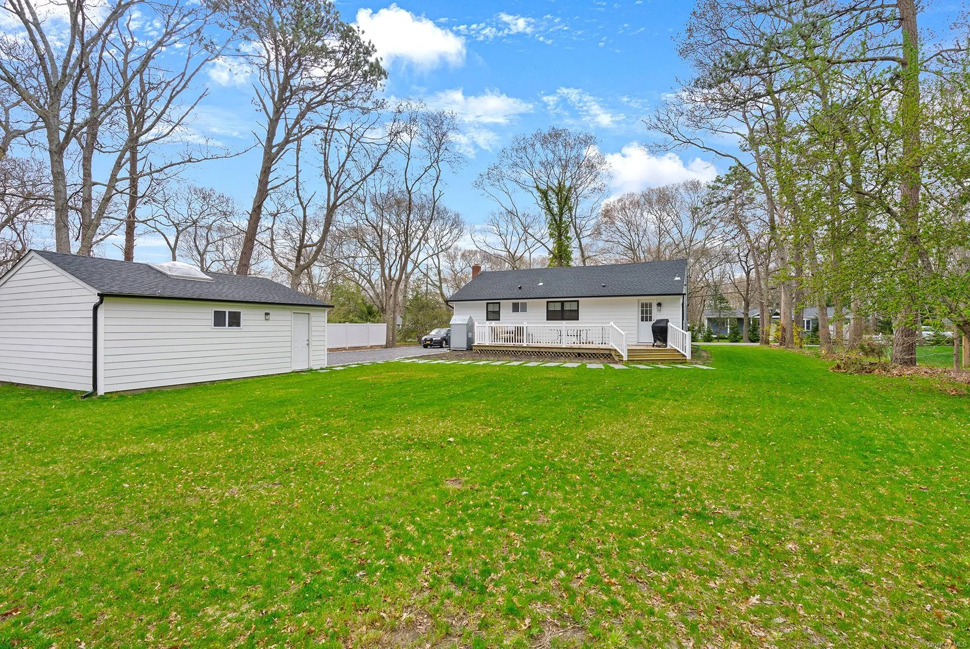 Back of house featuring a deck, a lawn, and an outbuilding Back of house featuring a deck, a lawn, and an outbuilding