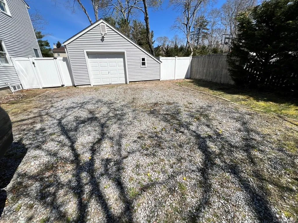 Detached garage featuring a gate, gravel driveway, and fence Detached garage featuring a gate, gravel driveway, and fence