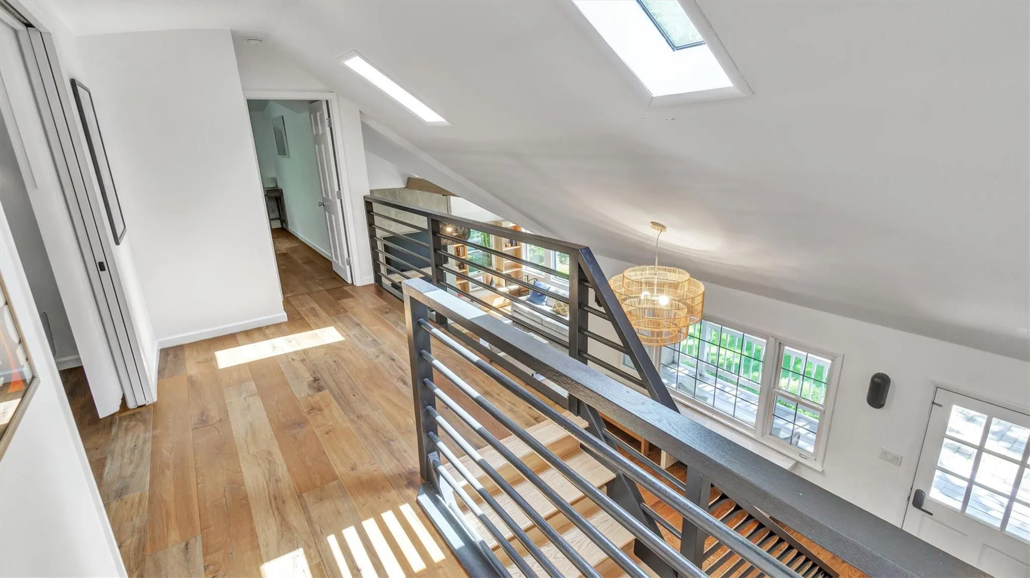 Hallway with a skylight, an upstairs landing, high ceiling, light wood-style flooring, and a chandelier. Hallway with a skylight, an upstairs landing, high ceiling, light wood-style flooring, and a chandelier.