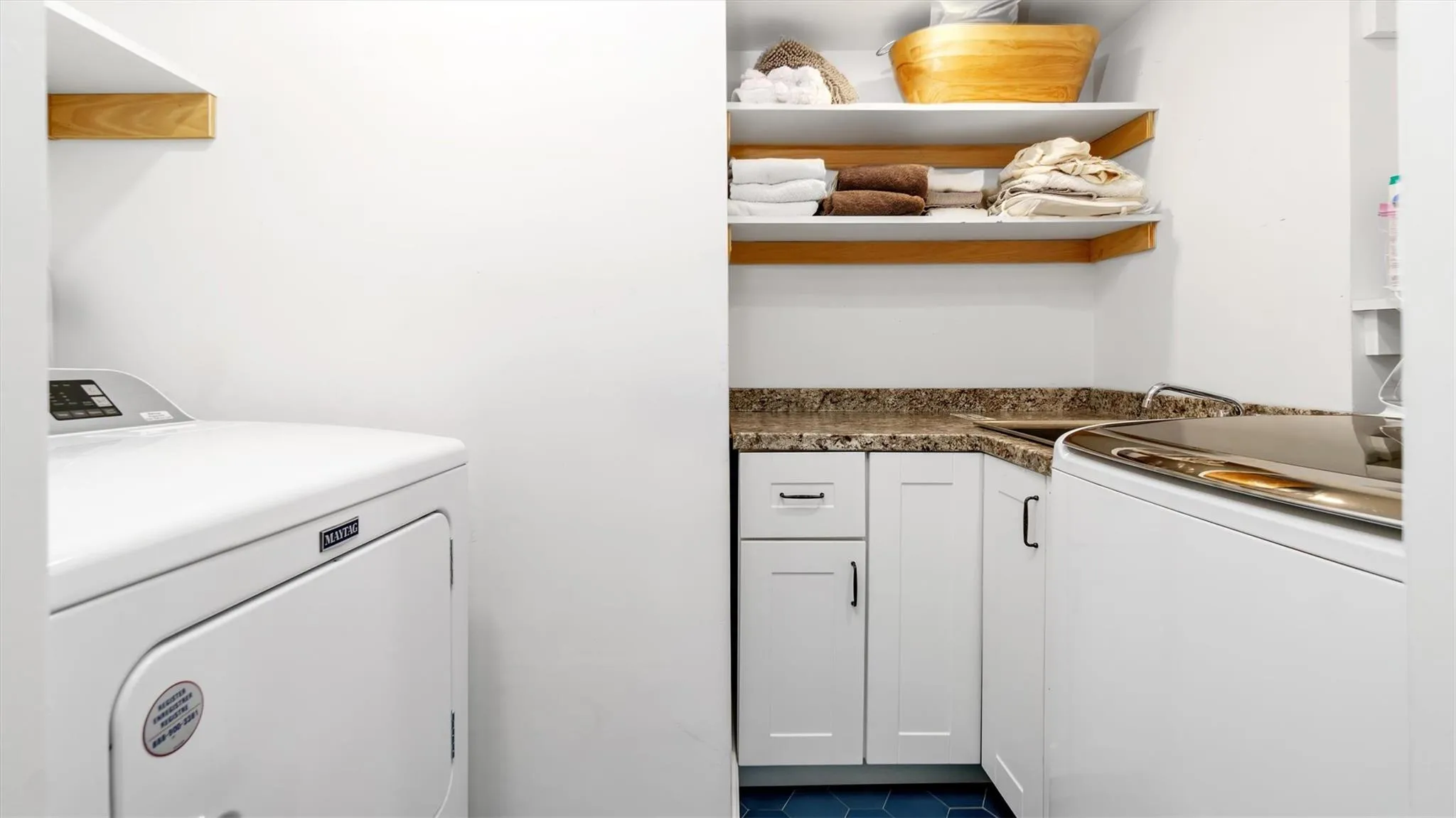 Laundry area with washing machine and clothes dryer, cabinet space, and dark patterned flooring. Laundry area with washing machine and clothes dryer, cabinet space, and dark patterned flooring.