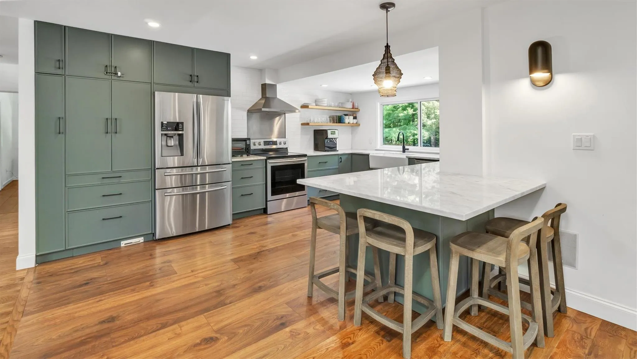 Kitchen featuring appliances with stainless steel finishes, wall chimney range hood, a sink, an and a kitchen breakfast bar. Kitchen featuring appliances with stainless steel finishes, wall chimney range hood, a sink, an and a kitchen breakfast bar.